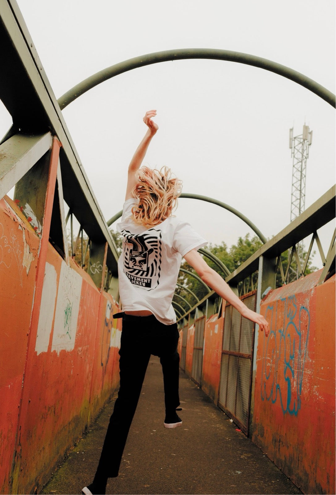 Uno skater in salto su una passerella coperta di graffiti